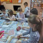 Na zdjęciu: Dzieci ozdabiają kartonowe ramki kolorowymi papierami i sznurkami.