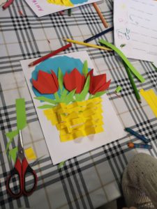 Na zdjęciu: Praca wykonana przez dziecko: papierowe czerwone tulipany w żółtym koszyku, na niebieskim tle.