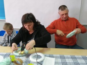 Na zdjęciu: Mężczyzna, kobieta i chłopiec kleją ozdabiają obręcze.
