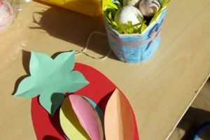 Na zdjęciu: papierowe kolorowe, jajko i koszyczek ze styropianowymi jajeczkami.