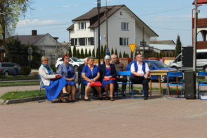 Na zdjęciu: Kobiety i mężczyżni ubrani na niebiesko siedzą na niebieskich krzesłach.