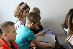 Na zdjęciu: Dzieci siedzą i przeglądają książkę.