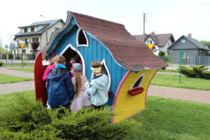 Na zdjęciu: Kilkoro dzieci wchodzi do kolorowego domku z pofalowanym dachem.