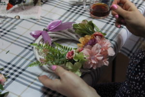 Na zdjęciu: Wianek z kolorowych, sztucznych kwiatów z różową wstążką.