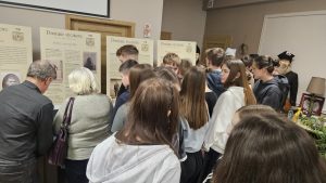 Grupa uczestników spotkania autorskiego oglądająca wystawę tematyczną