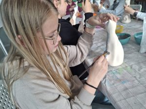 Dziewczynki podczas warsztatów szkliwienia ceramicznych figurek kota