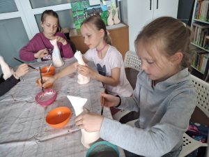 Dziewczynki podczas warsztatów szkliwienia ceramicznych figurek kota