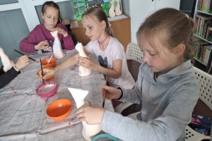 Dziewczynki podczas warsztatów szkliwienia ceramicznych figurek kota