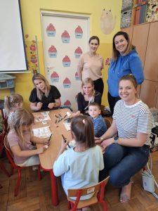 Grupa kobiet i dzieci malujących kamyki