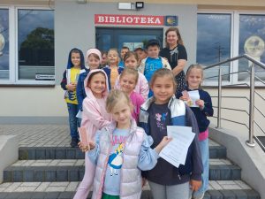 Dzieci i nauczycielka stoją przed biblioteką