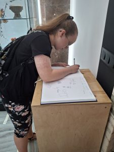 Dziewczyna wykonująca wpis pamiątkowy w muzeum
