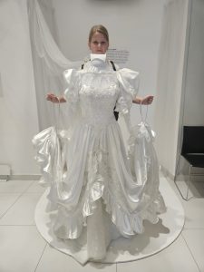 Dziewczynka pozująca z eksponatem sukienki w muzeum