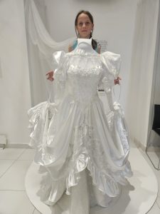 Dziewczynka pozująca z eksponatem sukienki w muzeum