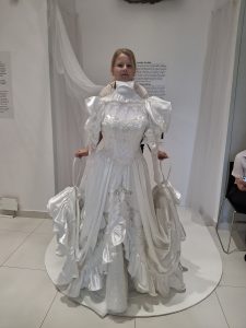 Dziewczynka pozująca z eksponatem sukienki w muzeum
