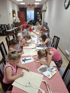 Grupa dzieci w trakcie warsztatów w bibliotece wraz z prowadzącą