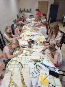 Grupa dzieci w trakcie warsztatów w bibliotece wraz z prowadzącą