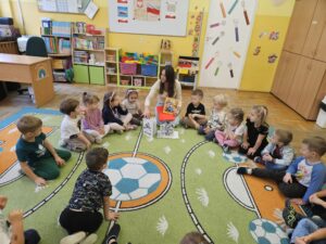 Kobieta oraz dzieci siedzące w kółku, na podłodze