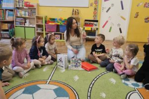 Kobieta oraz dzieci siedzące w kółku, na podłodze