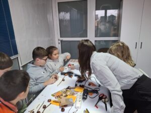 20251113_150536 Dzieci i kobieta na warsztatach, robiące ptaszki z kasztanów