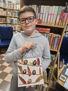 20251113_154409 Chłopiec trzymający obrazek z ptaszkami z kasztanów.