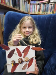20251113_154524 Dziewczynka trzymająca obrazek z ptaszkami z kasztanów.