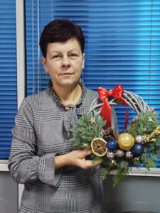 Kobieta ze świątecznym wiankiem w ręku.