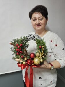 Kobieta ze świątecznym wiankiem w ręku.