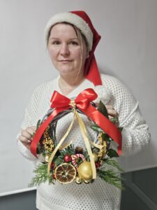 Kobieta ze świątecznym wiankiem w ręku.