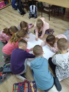 Dzieci rysują wspólnie choinkę.