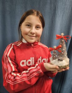 Zdjęcie przedstawia dziewczynkę pokazującą swoją pracę