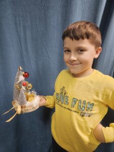 Zdjęcie przedstawia chłopca pokazującego swoją pracę