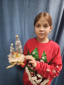 Zdjęcie przedstawia dziewczynkę pokazującą swoją pracę