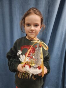 Zdjęcie przedstawia dziewczynkę pokazującą swoją pracę