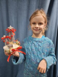 Zdjęcie przedstawia dziewczynkę pokazującą swoją pracę