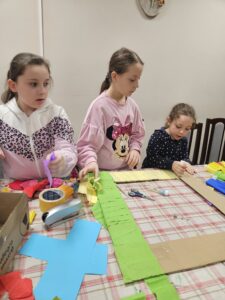 Dziewczynki ozdabiają ramy podczas warsztatów.