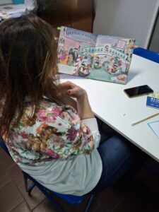 Prowadząca czyta dzieciom książkę o karnawale w Wenecji.