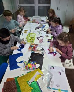 Dzieci na warsztatach tworzą maski karnawałowe.