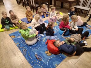 Dzieci siedzą na dywanie podczas lekcji bibliotecznej.