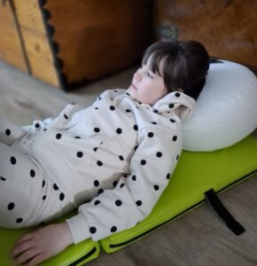 Dziewczynka leży na dywanie podczas lekcji bibliotecznej.