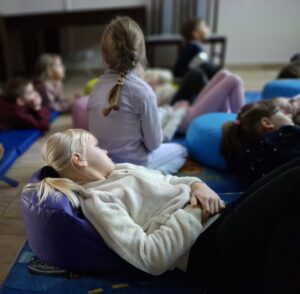 Dziewczyna leży na dywanie podczas lekcji bibliotecznej.
