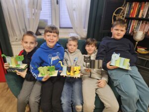 Chłopcy trzymający w rękach przyborniki z papieru w kształcie kota.