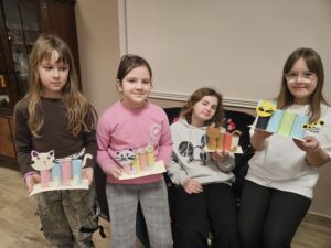 Dziewczynki trzymający w rękach przyborniki z papieru w kształcie kota.