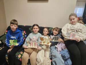 Chłopiec i dziewczynki trzymający w rękach przyborniki z papieru w kształcie kota.