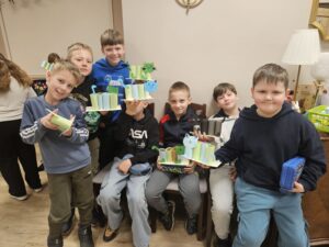 Chłopcy trzymający w rękach przyborniki z papieru w kształcie kota.