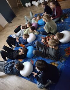 20260225_084116 Dzieci siedzą na dywanie i oglądają prezentację.