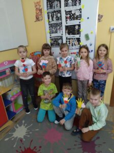 Grupa dzieci z papierowymi drzewkami.