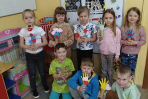 Grupa dzieci z papierowymi drzewkami.