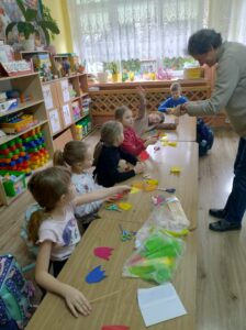 Dzieci i instruktorka podczas warsztatów robienia tulipanów z papieru.