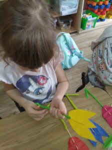 Dziewczynka podczas warsztatów robienia tulipanów z papieru.