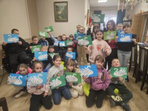 Grupa dzieci prezentująca swoje prace plastyczne - łabędzie.